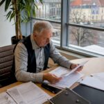 Ein Immobilienverwalter prüft im Büro sorgfältig die Vertragsunterlagen.