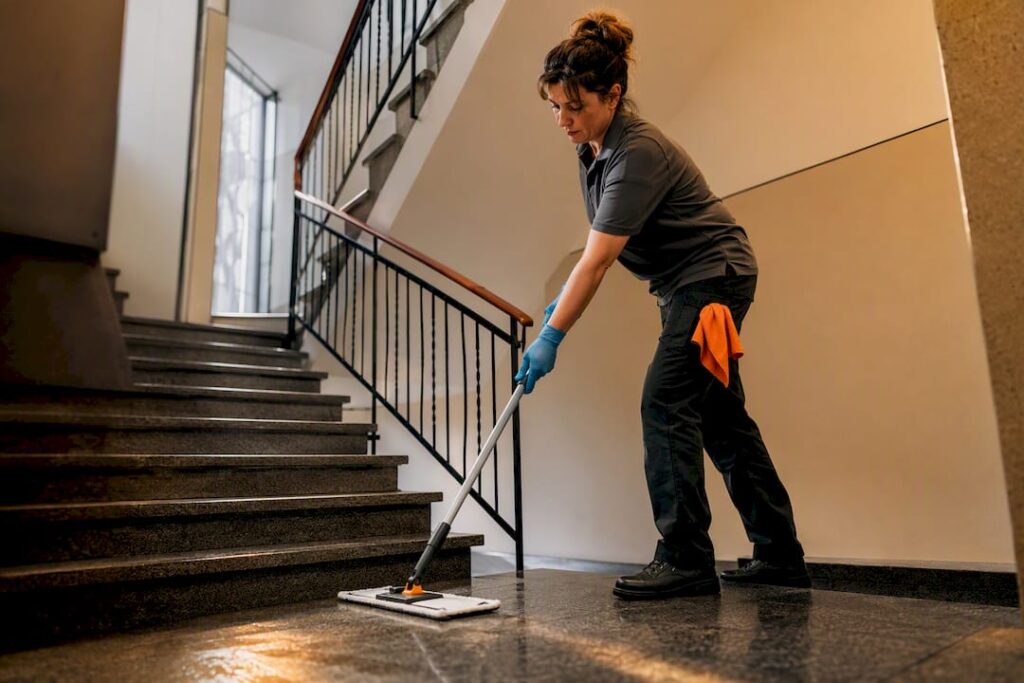 Putzkraft wischt die Treppenstufen im Mehrfamilienhaus