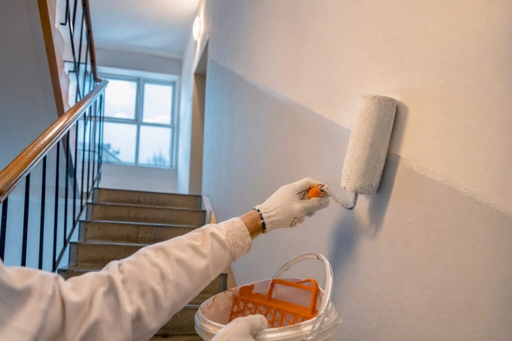 Maler streicht die Wand im Treppenhaus