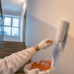 Maler streicht die Wand im Treppenhaus